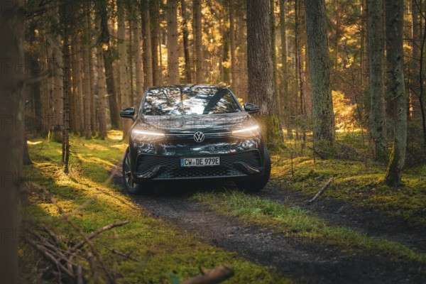 Car driving along a wooded path in a warm autumn atmosphere, car sharing vehicle Deer Mobility, electric car VW ID5, Black Forest, Germany, Europe