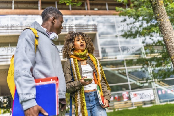 Low angle view photo of two male and female multiethnic students walking along the university campus and talking