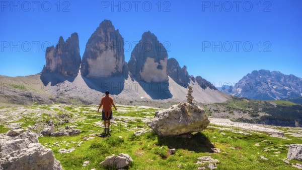 Tourist enjoying the breathtaking view of the tre cime di lavaredo peaks while hiking in the italian dolomites on a sunny summer day