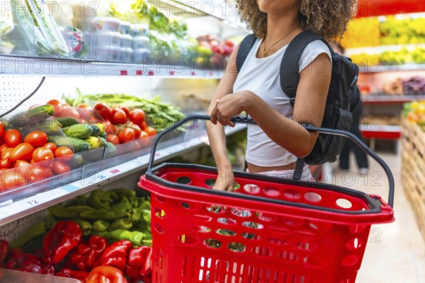 Cropped photo of an unrecognizable latin young woman buying in a supermarket using basket