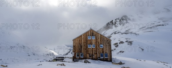 Chamanna Es-cha mountain hut in a cloudy winter mountain landscape, Bündner Haute Route ski tour, Albula Alps, Rhaetian Alps, Grisons, Eastern Switzerland, Switzerland, Europe