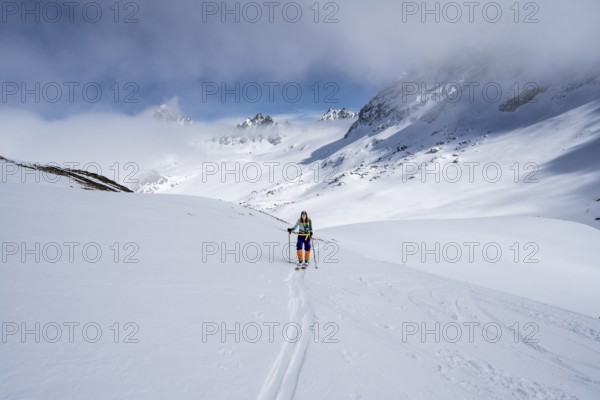 Ski tourer ascending through a picturesque snow-covered mountain landscape with views of mountain peaks, ascent to the summit of Kesch Pitschen, Bündner Haute Route ski tour, Albula Alps, Rhaetian Alps, Grisons, Eastern Switzerland, Switzerland, Europe
