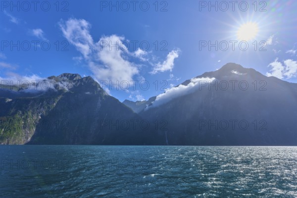 Bright sun over majestic mountains and calm sea, summer, Milford Sound, Te Anau, Fiordland National Park, South Island, New Zealand, Oceania