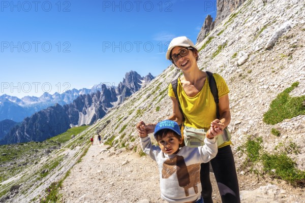 Mother and son enjoying a summer hike in the italian dolomites, surrounded by breathtaking mountain scenery