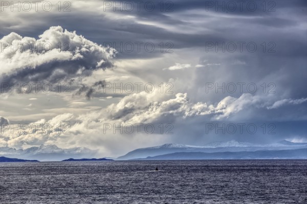 View from the deck of the cruise ship to a dramatic cloudy sky and distant mountains in the background, Chile, South America