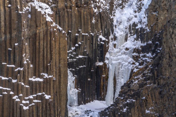 Hengifoss waterfall frozen in the cold winter of Iceland, volcanic cliffs