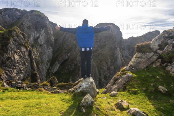Hiker celebrating at the summit of aiako harria mountain in oiartzun, gipuzkoa, basking in stunning views and achievement