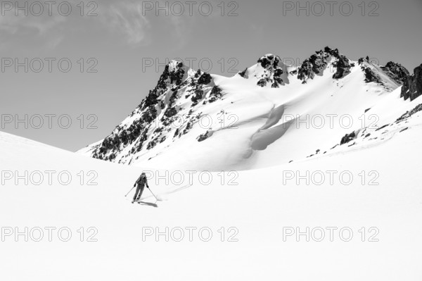 Ski tourer on the descent, minimalist winter landscape, white snow and dark mountains on the Scalettahorn, Graubünden, Switzerland, Europe