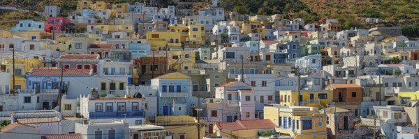 Panorama of the village of Menetes with densely built pastel-coloured houses on a Mediterranean slope, Menetes, Karpathos, Greece, Europe
