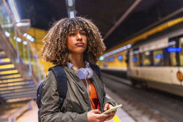 Beauty latina young woman using phone while waiting for the train in an underground platform