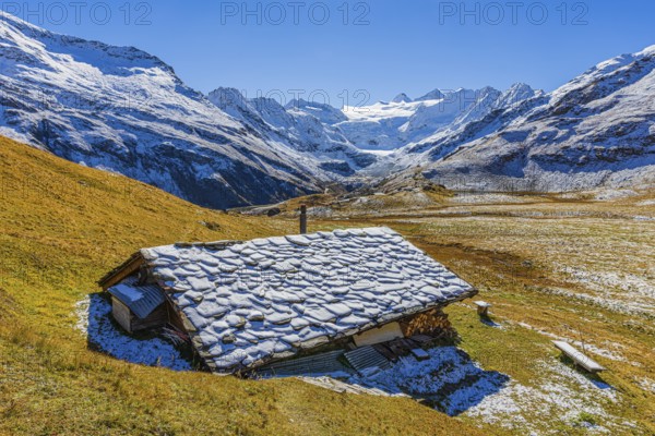 Alpine hut with snow-covered roof, slightly snow-covered alpine meadow, behind the Moiry glacier, near Grimentz, Val d'Anniviers, Valais Alps, Canton Valais, Switzerland, Europe