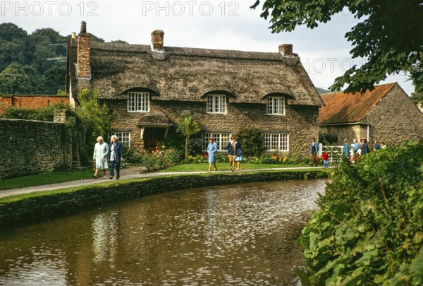 Touristen spazieren am attraktiven reetgedeckten Beck Isle Cottage, Thornton Beck stream, Thornton le Dale, north Yorkshire, England, UK 5 September 1974