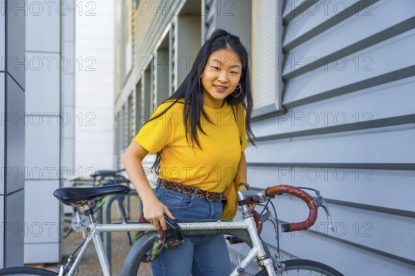 Portrait of a young chinese cute woman parking a bike in the street