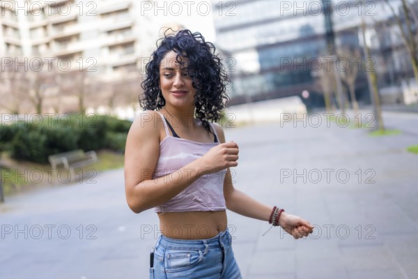 Carefree young woman dancing in the city wearing casual clothes, enjoying the urban environment