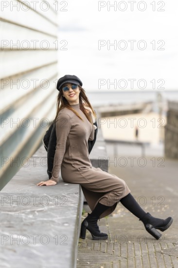 Stylish woman enjoying a moment of relaxation on a bench, embracing the coastal atmosphere with her trendy outfit