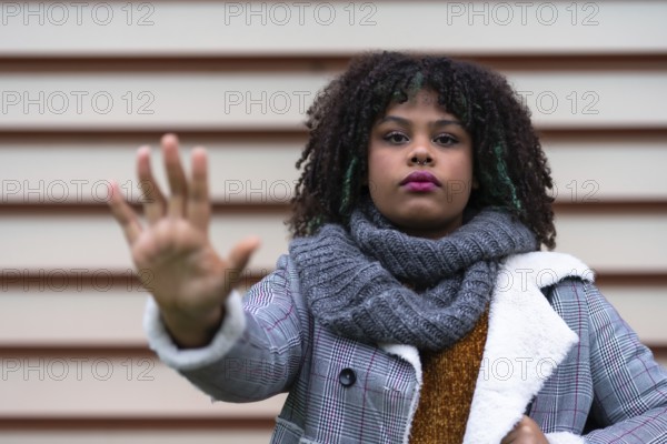 Black ethnic woman making a stop racism gesture on a gray wall