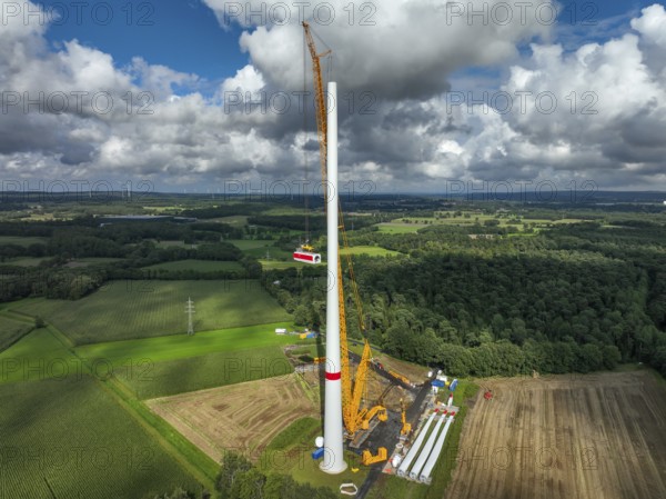 Dorsten, North Rhine-Westphalia, Germany, construction of a wind turbine, the first wind turbine of the Große Heide wind farm. A large mobile crane places the nacelle, the nacelle on the tower. The rotor blades, vanes and rotor hub are ready for assembly, Europe