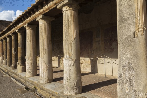 Old large building covered with terracotta clay roof tiles and supported by stone columns at the ancient ruins of Pompeii, Campania region, Italy, Europe