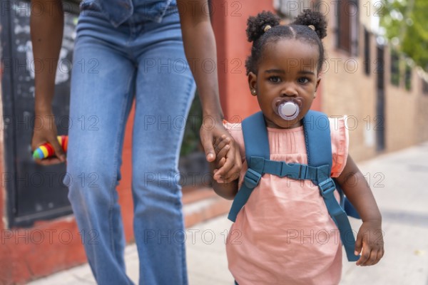 African mother and baby girl walking holding hands in the street