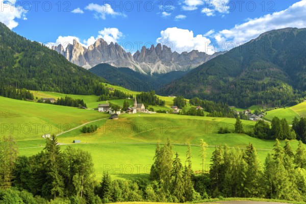 Green meadows blanket the valley in front of santa maddalena village, framed by the stunning odle mountain group in the dolomites
