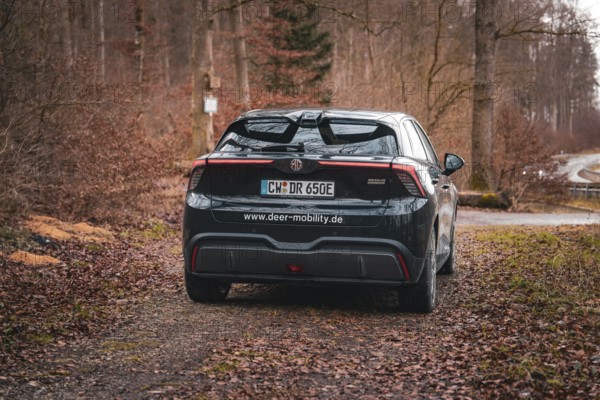 Black electric car on a forest path in autumn from behind, e-car sharing vehicle from Deer Mobility, Gechingen, Black Forest, Germany, Europe
