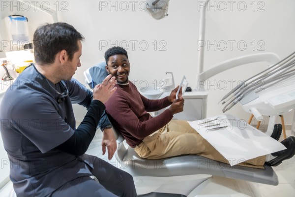Dentist explaining a dental x ray to a patient sitting in a dental chair, discussing a treatment plan in a modern dental clinic