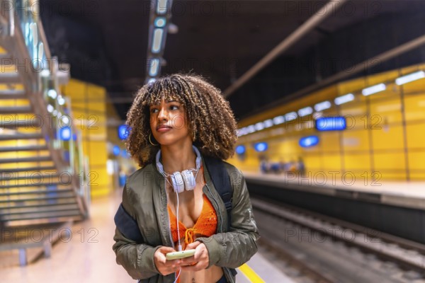 Latin beauty young female student waiting the metro in the platform and using phone