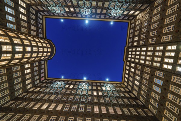 Symmetrical inner courtyard of a Kontorhaus with illuminated rows of windows at night, Hamburg, Germany, Europe