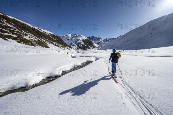 Ski tourer in the snow by a mountain stream in the Funtauna Valley, Graubünden Haute Route, Albula Alps, Rhaetian Alps, Graubünden, Switzerland, Europe
