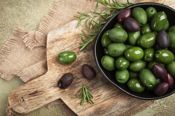 Chalkidiki olives, classic Greek green olives, in a bowl on a cutting board, top view, without people
