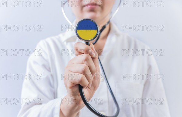 Female doctor holding stethoscope with Ukraine flag. National Health System of Ukraine