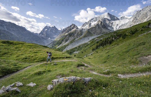 Mountaineer on a hiking trail, mountain landscape near Arolla, in the background mountain peak Mont Collon and glacier Glacier de Tsijore Nouve, Valais, Western Alps Switzerland