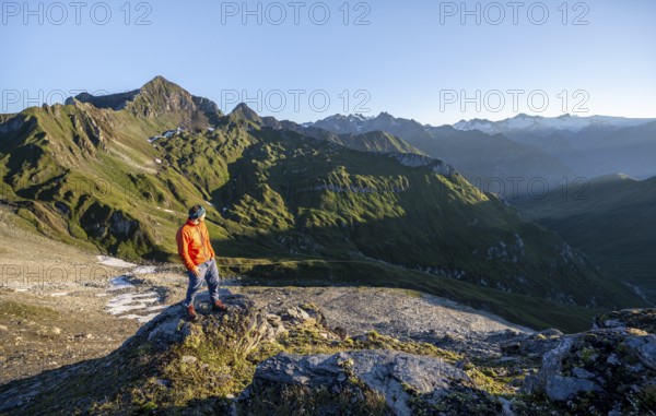 Mountaineer in front of mountain landscape at sunrise, view of mountain peaks of the Venediger group and into the Großbachtal valley from the summit of Bachlenkenkopf, Lasörling group, Hohe Tauern National Park, East Tyrol, Tyrol, Austria, Europe