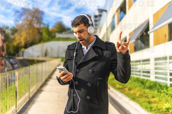 Mature man in elegant clothes enjoying listening rock music outdoors in the city