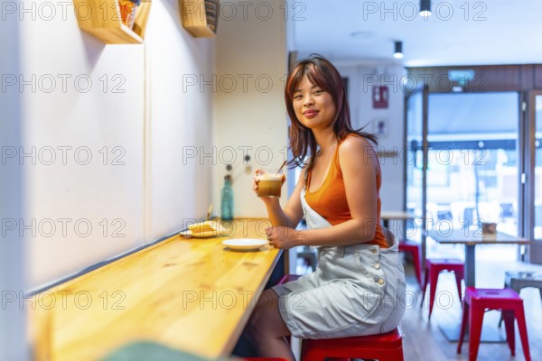 Side view portrait with copy space of a casual woman sitting on a cafeteria drinking morning coffee