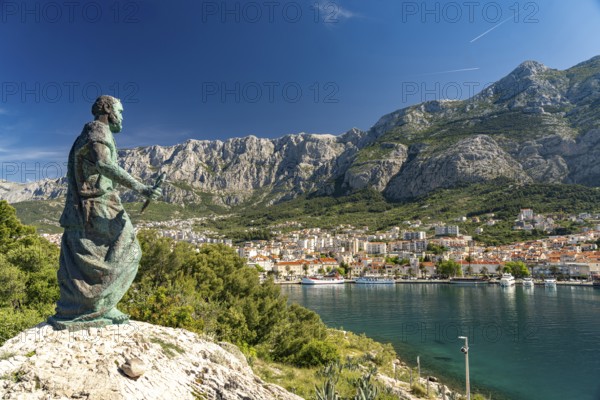 Statue of St Peter in front of the city view of Makarska and the Biokovo Mountains, Croatia, Europe