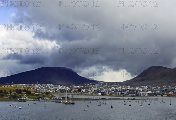 View of Ushuaia with sailing boats in front of cloudy mountains and cloudy sky, Ushuaia, Argentina, South America