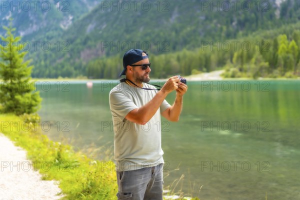 Tourist taking photos of the landscape at lake dobbiaco during summer holidays in the italian dolomites