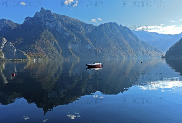 Lonely boat anchored on the mirror-smooth water of Lake Lake Traun, Traunkirchen, Salzkammergut, Austria, Europe