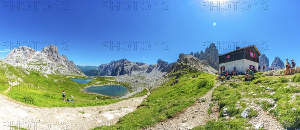 Tourists enjoying breathtaking views while hiking near the tre cime di lavaredo peaks and mountain hut in the italian dolomites during summer. Laghi dei Piani