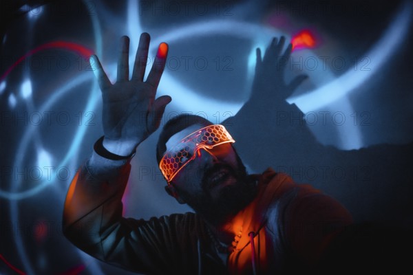 Cyberpunk man wearing illuminated goggles interacting with virtual reality game using augmented reality technology