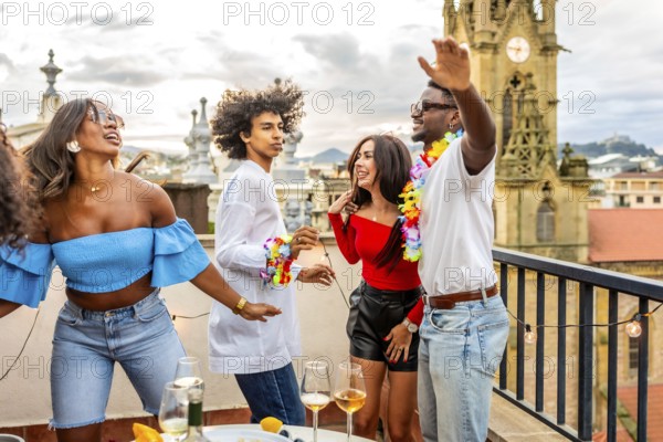 Happy multi-ethnic friends dancing together in a rooftop party at evening