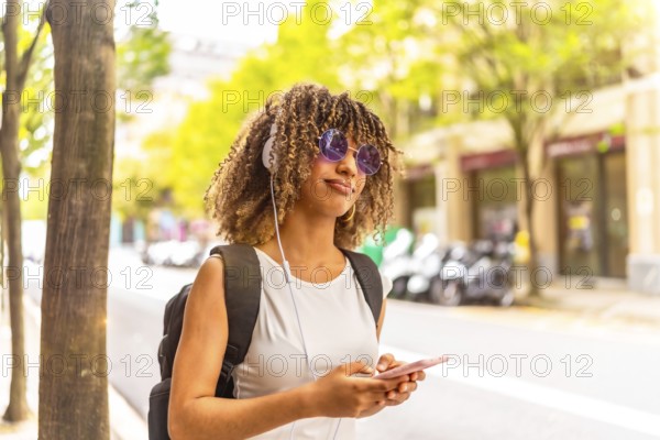 Side view close-up with copy space portrait of a latin cheerful woman listening to music using phone in the street