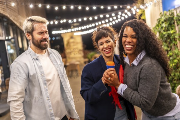 Multi-ethnic diverse friends enjoying singing karaoke outdoors in a bar terrace