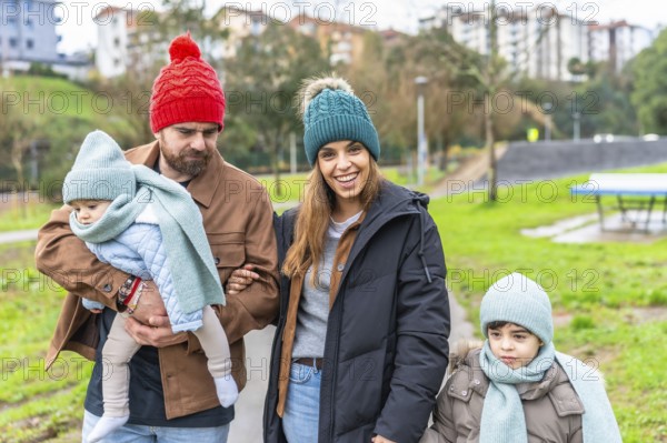 Smiling family enjoying a delightful winter walk in the park, bundled up in warm hats and scarves, sharing moments of joy and togetherness