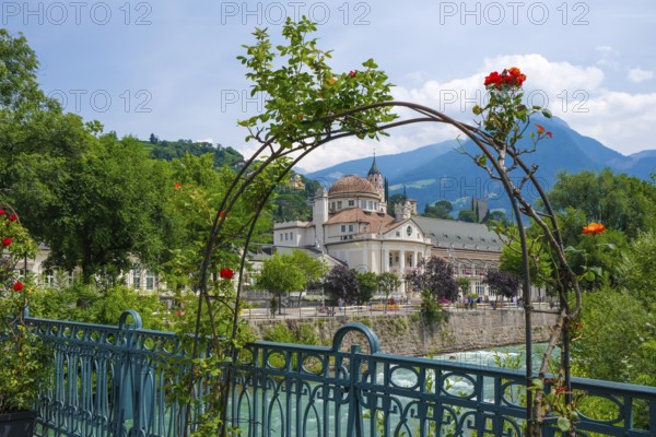 Merano, South Tyrol, Italy, spa hotel on the river Passer, on the Passer promenade in the old town centre. Red roses in front on the thermal bridge, Europe