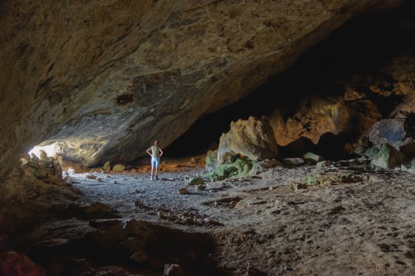 Woman in the darkness of the vast Limniatis Cave, Hike from Aperi to Limniatis Cave, Limniatis Cave, Aperi, Karpathos, Greece, Europe