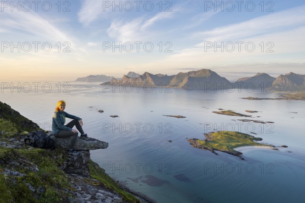 Hiker looking at the coast and mountains of Lofoten, Norway, Europe
