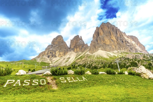 Green meadow with passo sella sign and the sassolungo group in the background, dolomites, italy
