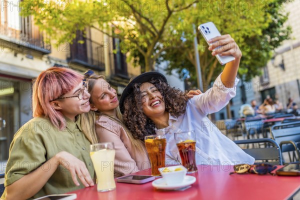 Three female beauty travelers taking selfie enjoying beverages on an outside cafeteria